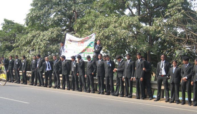 A group of spirited students standing in line along the roadside, proudly holding a banner.